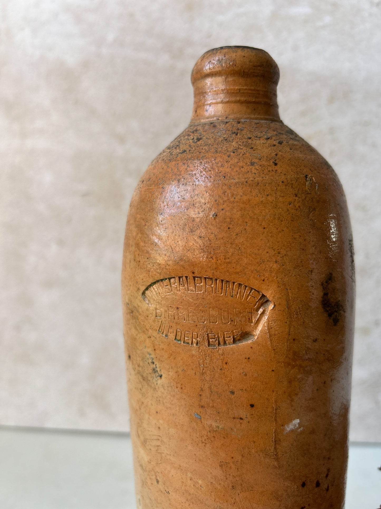 Brown ceramic bottle with visible branding on a textured white background