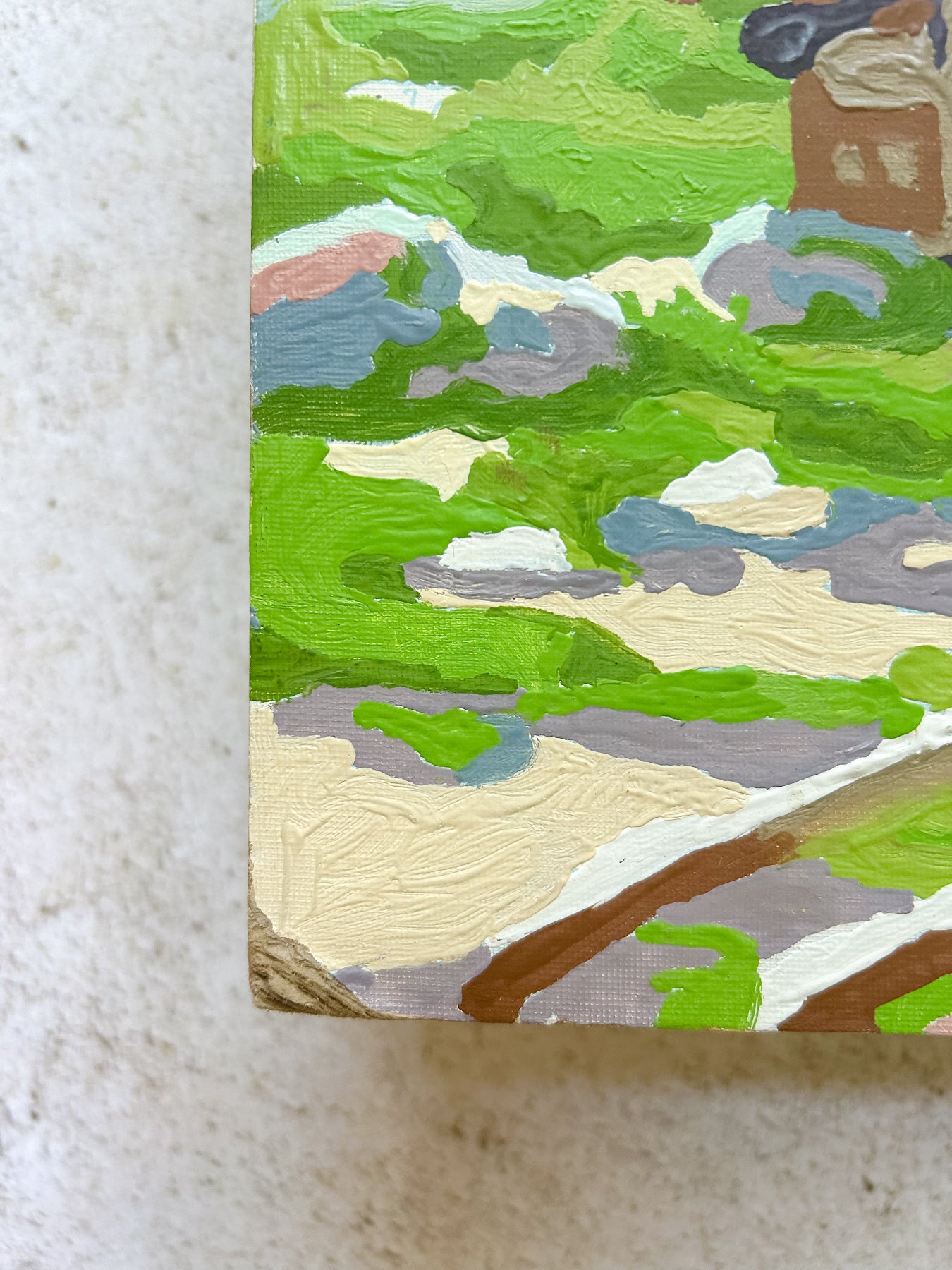 Small painting of a landscape with green fields and a building on a textured surface