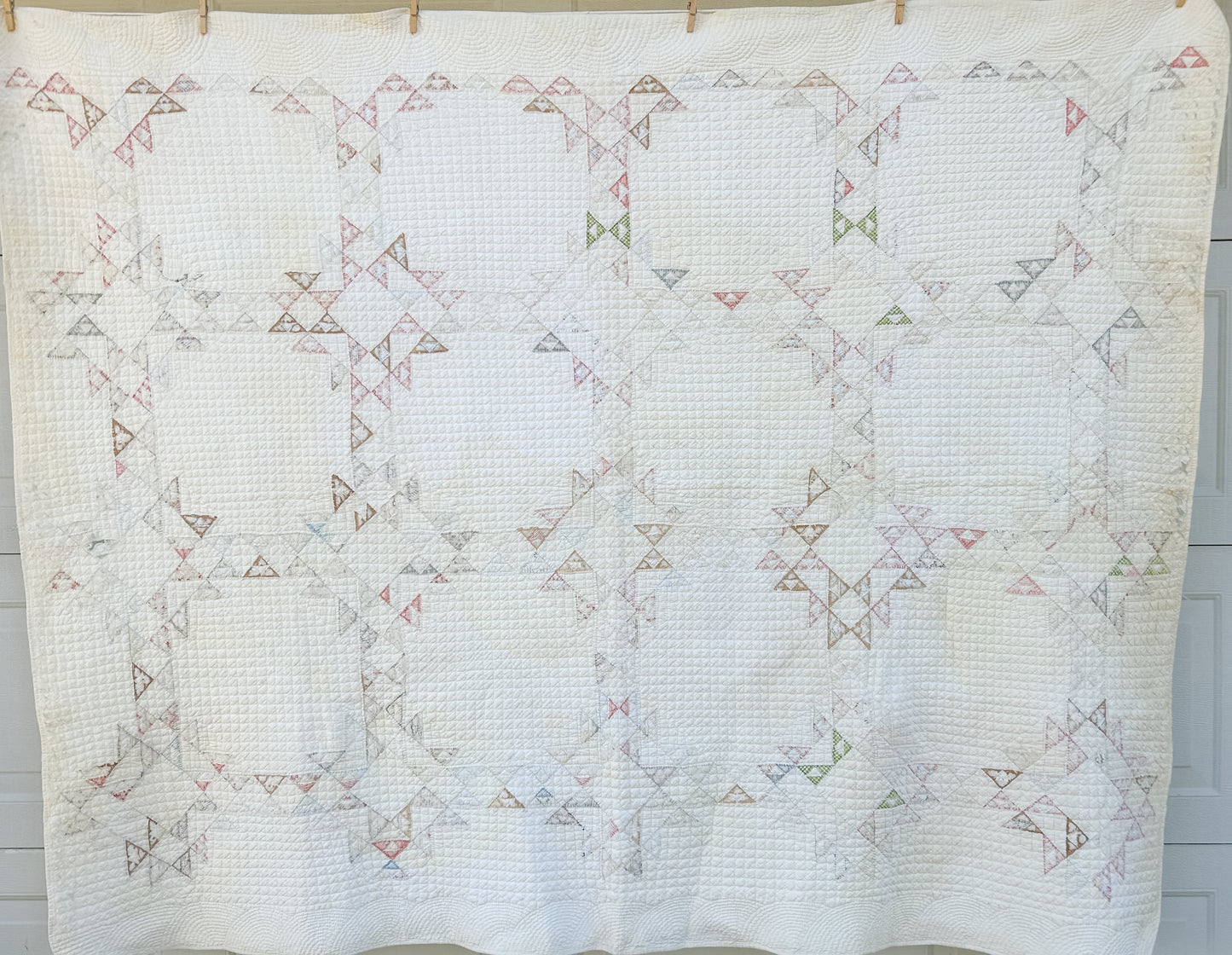 Quilt with geometric pattern hanging on a line against a neutral background