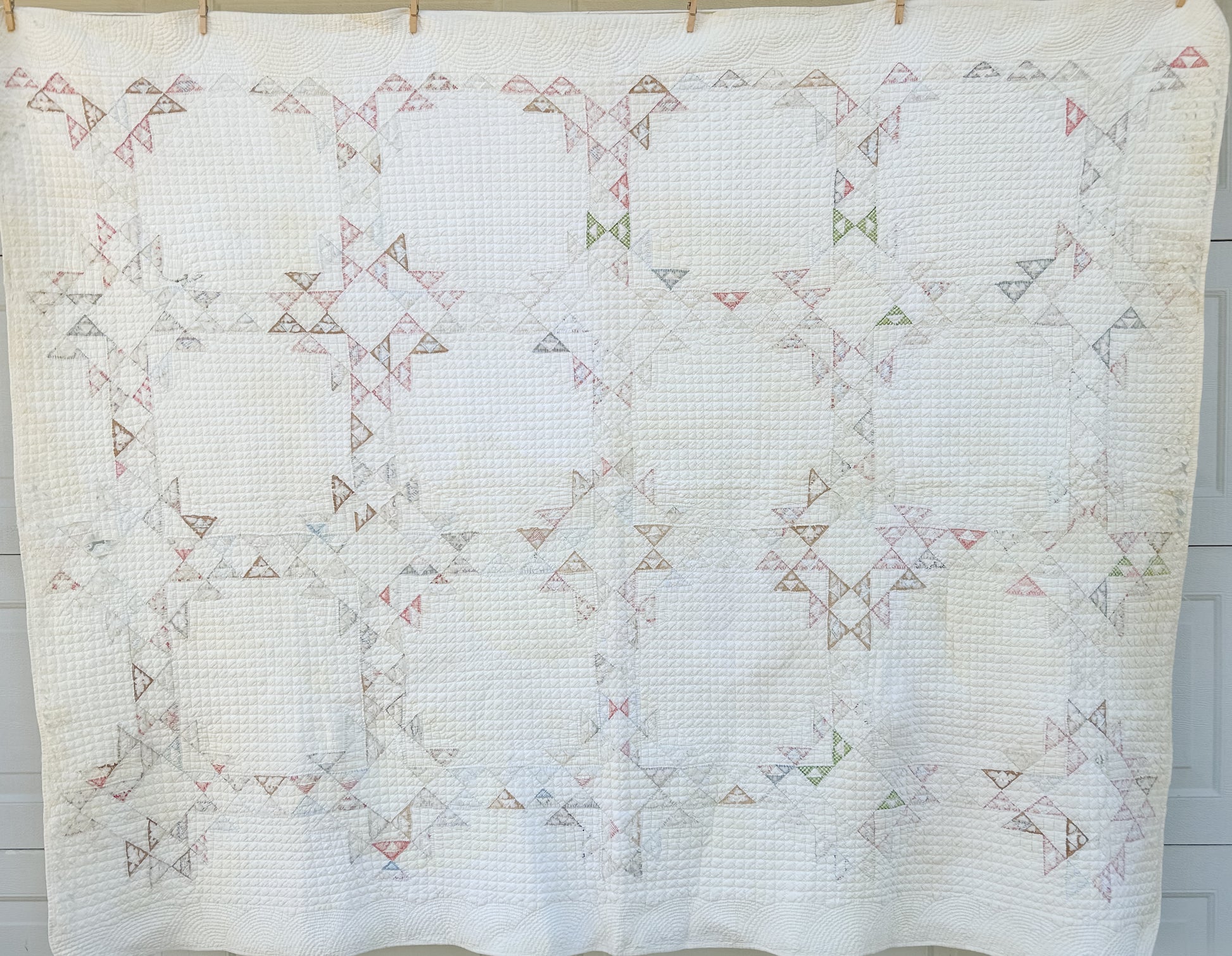 Quilt with geometric pattern hanging on a line against a neutral background